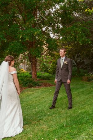 A romantic wedding moment captured in a lush green garden setting with a couple in formal bridal attire.
