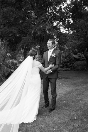A romantic wedding couple dances and spins together on green grass in a garden setting during their special day.