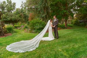 Bride and groom share romantic moments in lush garden setting with elegant flowing wedding dress train.
