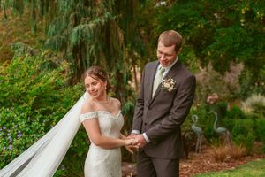 A couple shares an intimate moment together in a lush garden setting during their wedding ceremony.