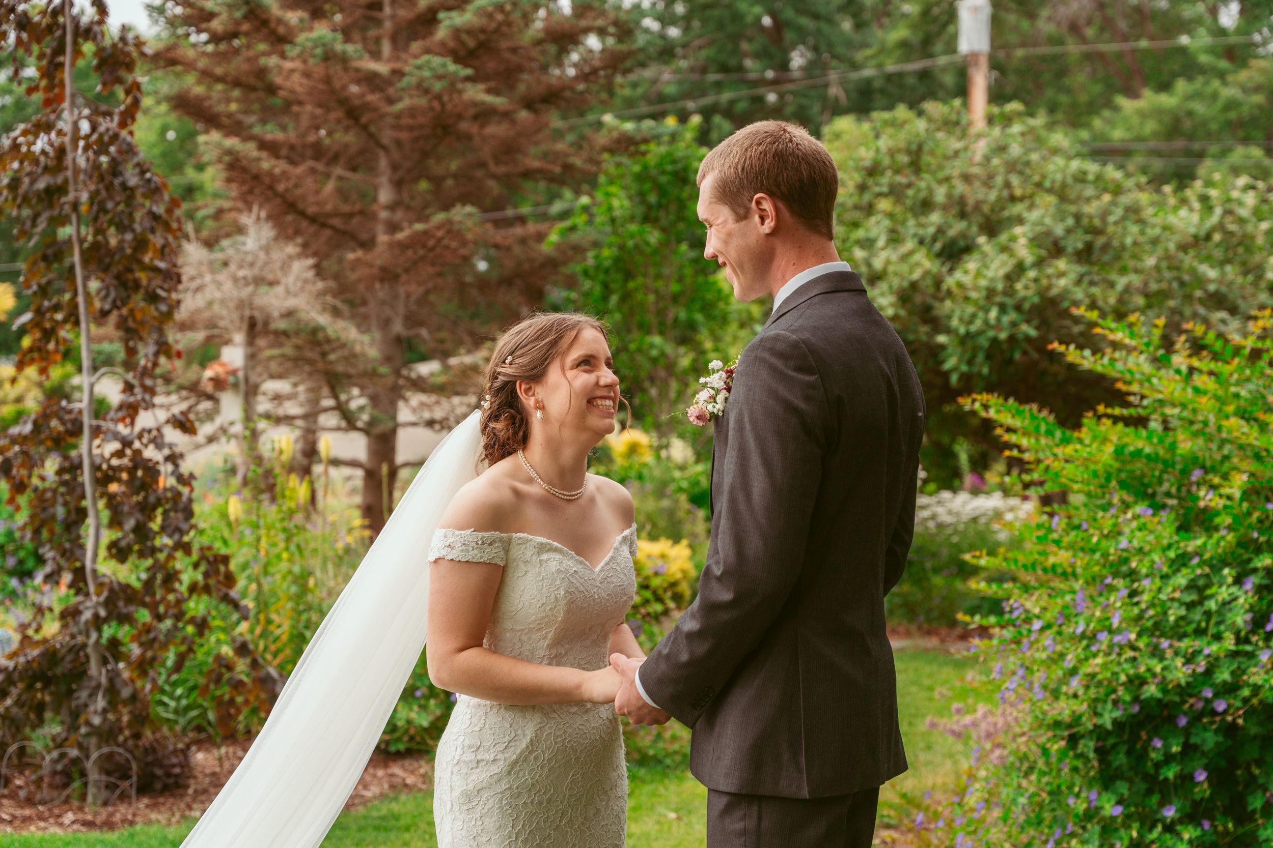 A bride and groom share an intimate moment during their outdoor wedding ceremony surrounded by lush greenery.