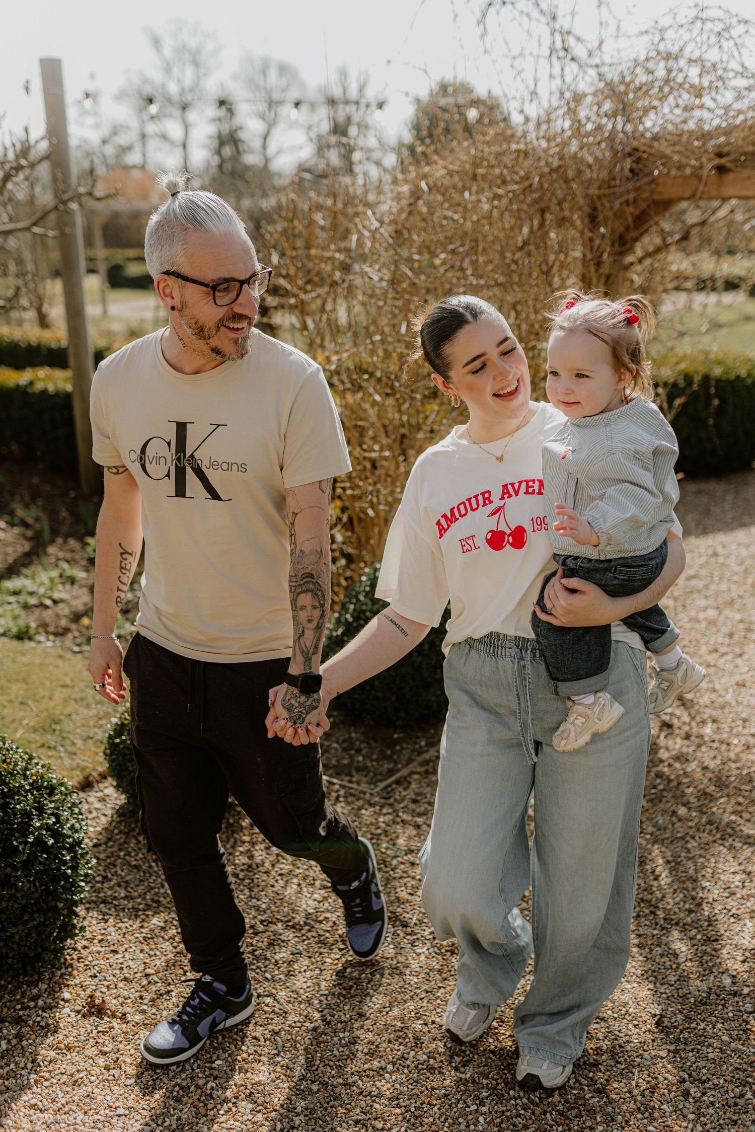 A family enjoys a casual stroll together along a garden path on a sunny afternoon.