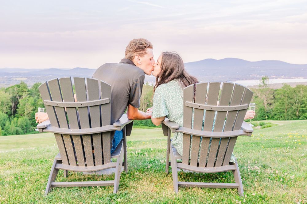 Two Adirondack chairs overlooking scenic mountain views on a tranquil spring day at sunset.
