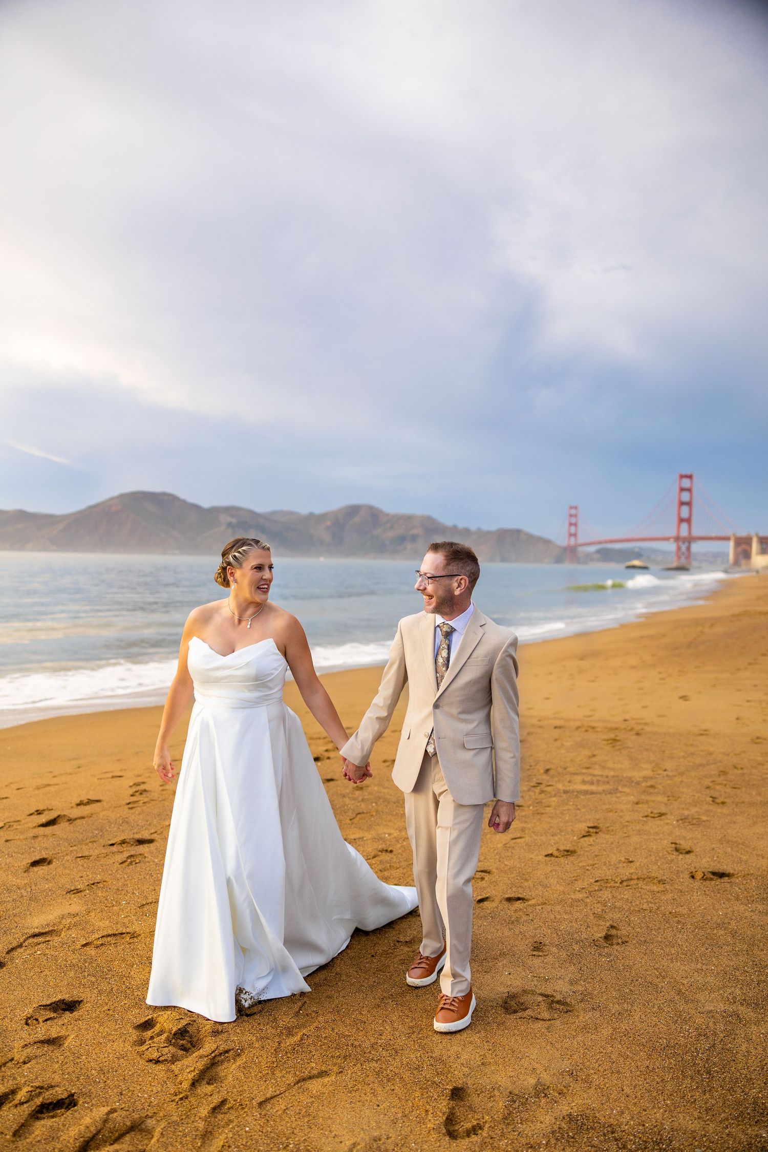 Wedding photos on beach with Golden Gate Bridge visible in background.