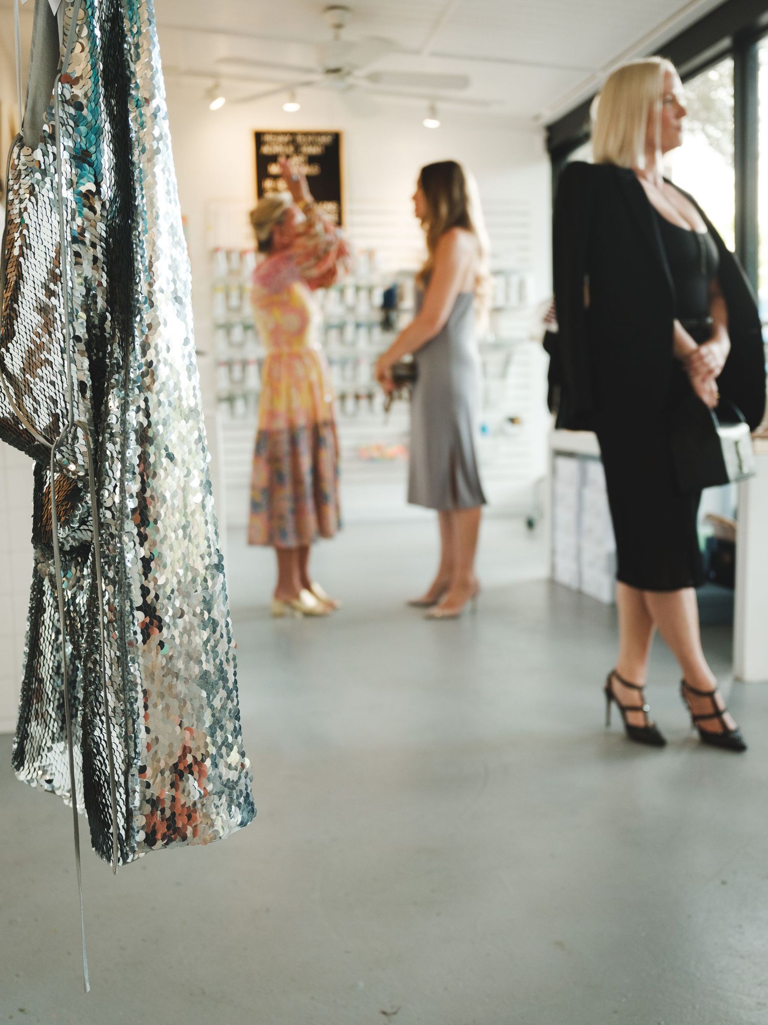 Art gallery space with silver tinsel decorations and people browsing exhibits.
