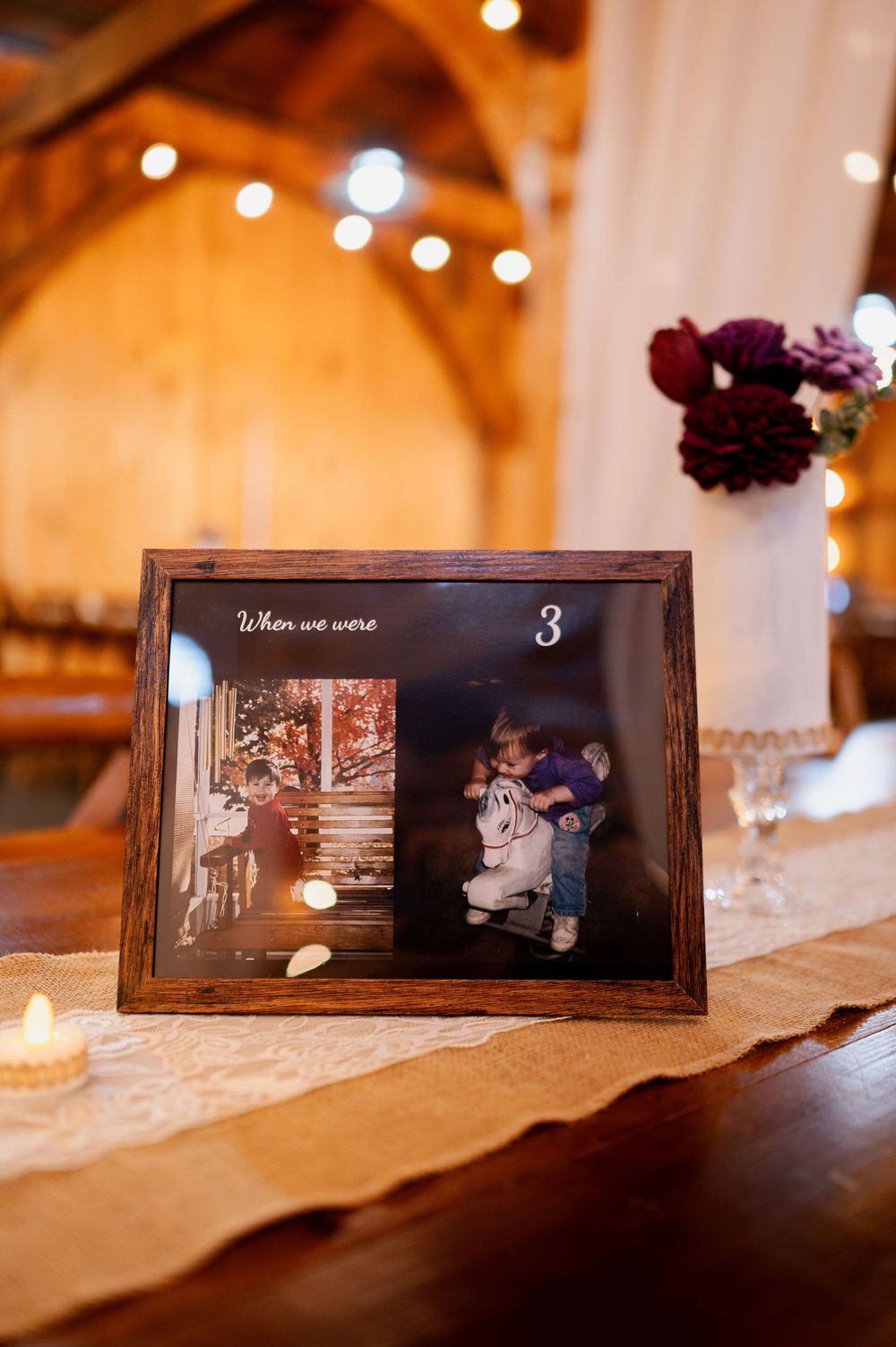 Framed vintage photos displayed as table decor at a wedding reception with burgundy flowers and string lights.
