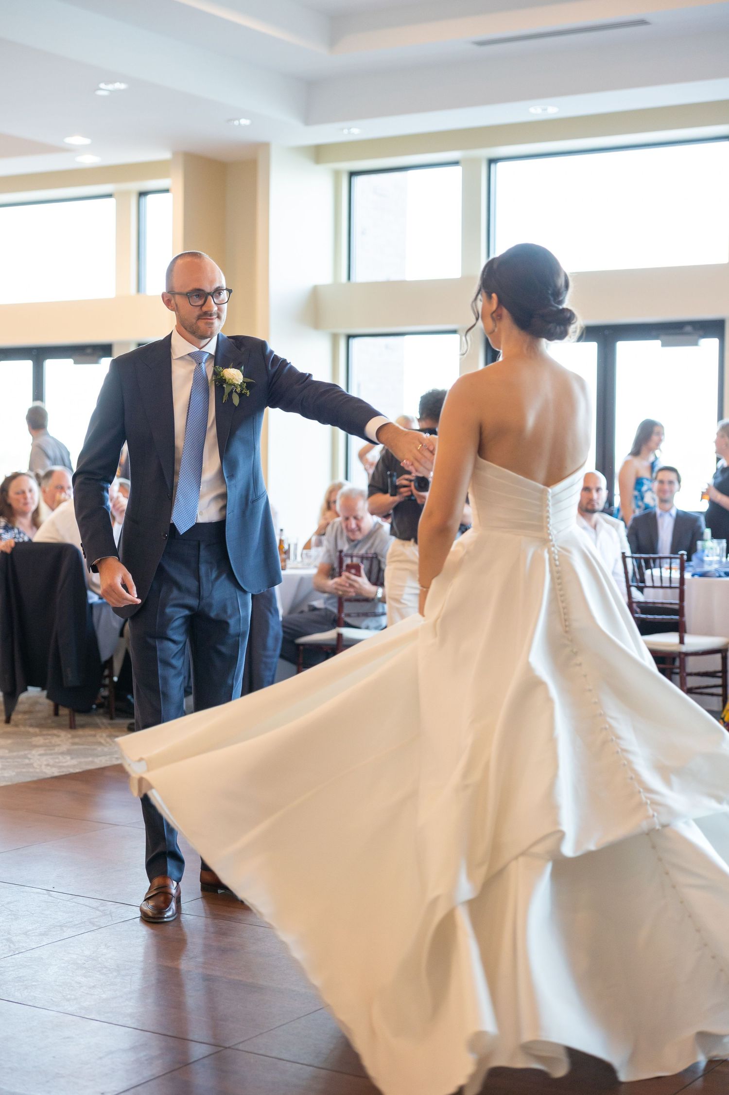Wedding guests celebrate with a joyful reception dance as the bride's white dress twirls elegantly on the dance floor in St. Clair Michigan