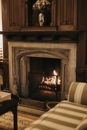 Elegant stone fireplace glowing with warm flames in a traditional room interior with white mantle and molding details.