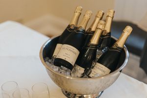 Champagne bottles chilling in an elegant silver ice bucket with empty glasses beside it.