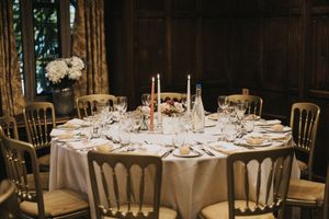 Elegant wedding reception venue with round tables set with white linens and floral centerpieces in a grand ballroom setting.
