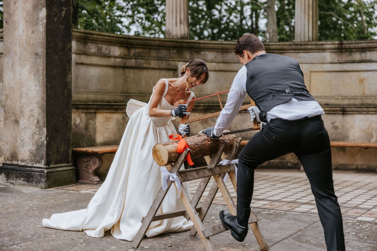 Wedding couple pours wine together in an outdoor ceremony at a stone courtyard.
