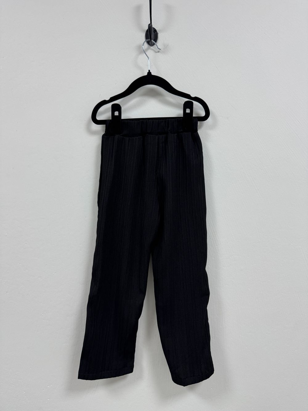 Black sports shorts with pockets displayed on three different hangers against a plain white background.
