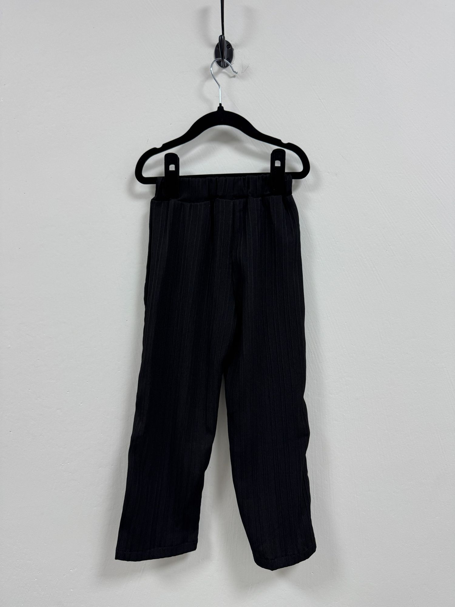 Black sports shorts with pockets displayed on three different hangers against a plain white background.