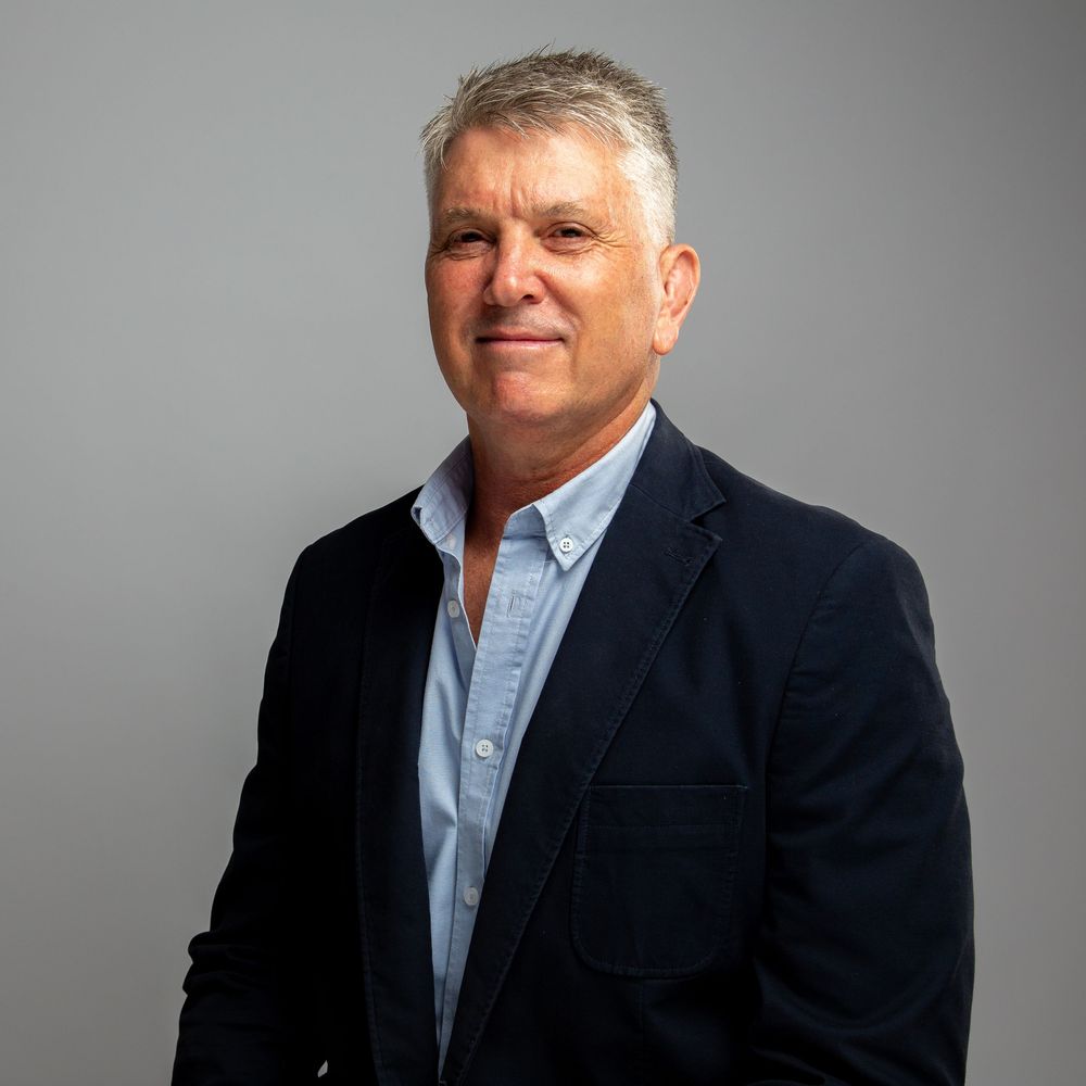 Professional headshot series showing different angles of a person in a navy blazer and light blue shirt against gray background.