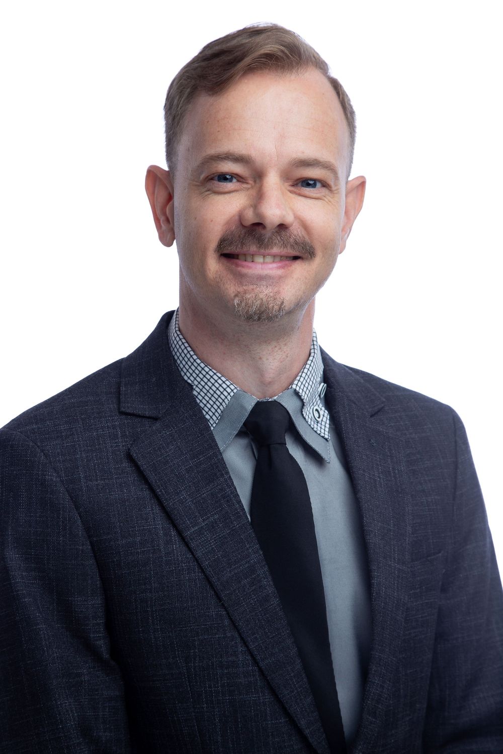 Professional wearing a dark suit and checkered dress shirt poses casually in a series of headshot expressions.