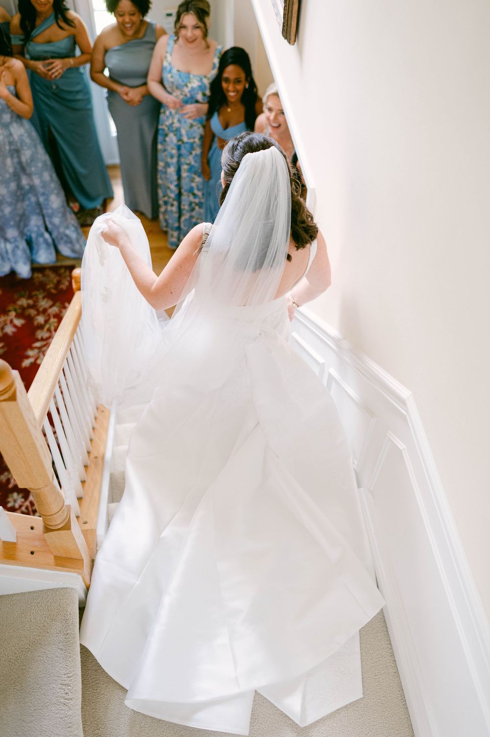 A wedding dress with flowing train photographed from above on wooden stairs.