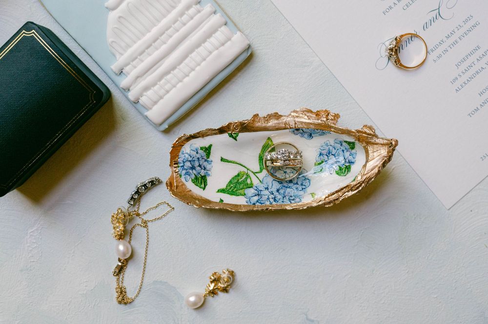 Vintage floral dish with jewelry and wedding details on white surface.