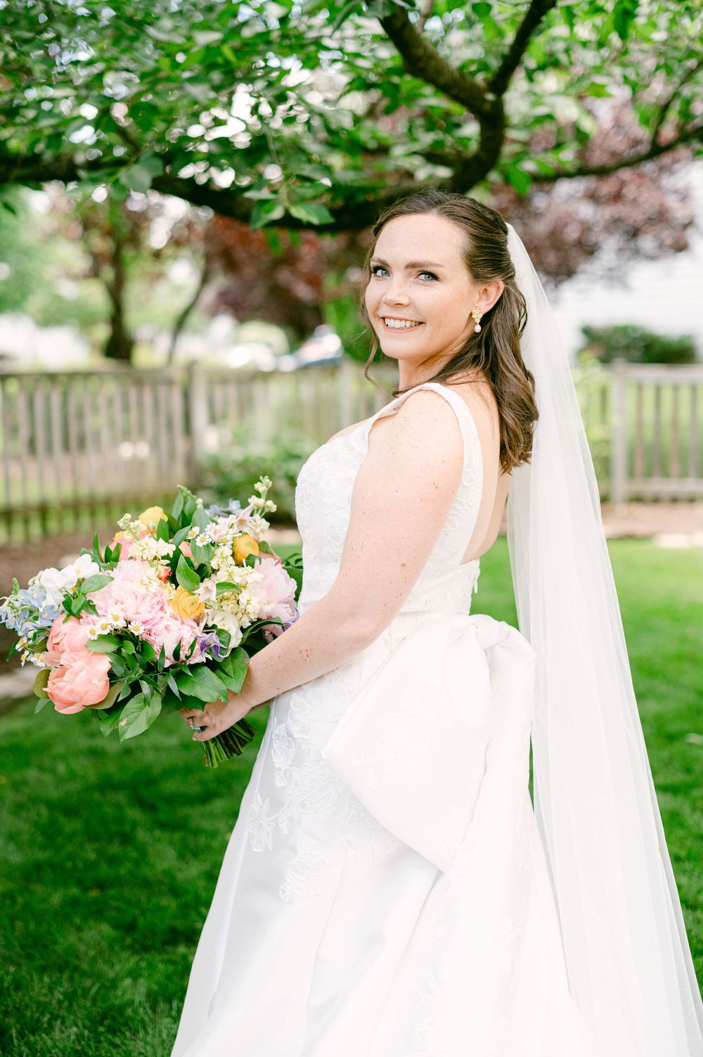 A beautiful wedding portrait in a garden setting with a pastel floral bouquet.