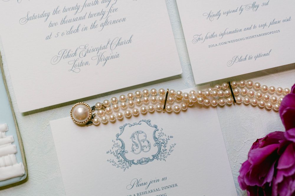 Elegant wedding invitation suite with pearl necklace and purple floral accents.