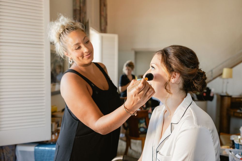 Getting ready scene with bridesmaids in natural light room before wedding ceremony.