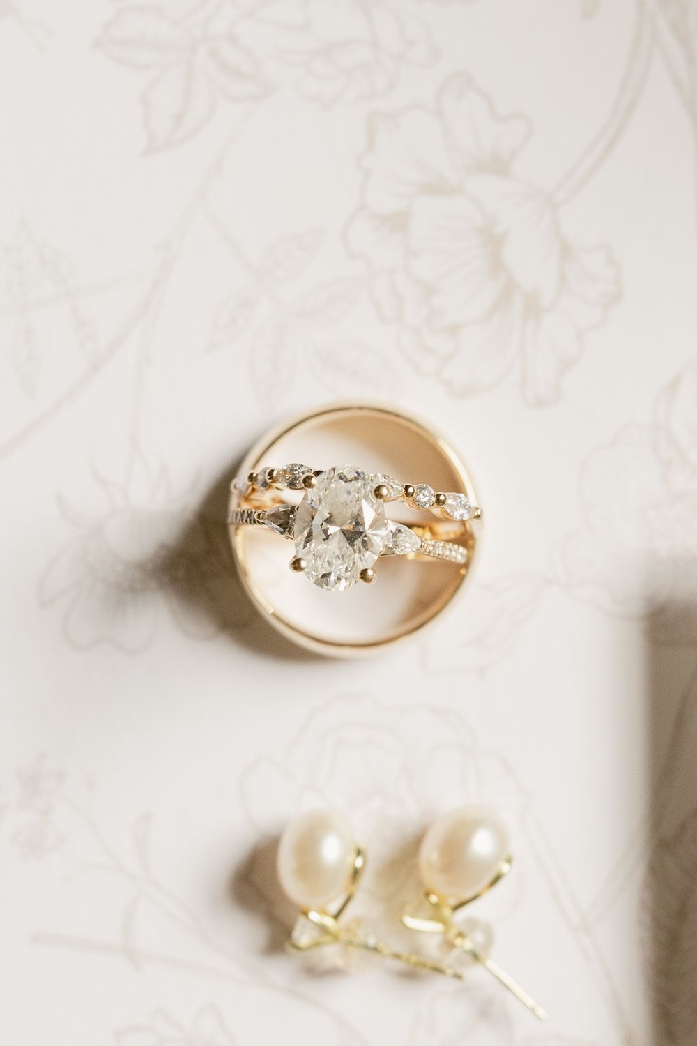 Wedding jewelry set featuring a sparkly diamond ring and pearl earrings on white textured fabric.