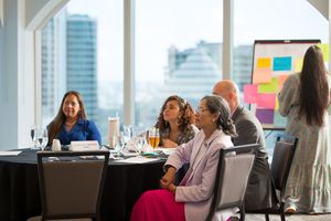 Business people collaborate and engage in discussion at a modern office meeting room with large windows.