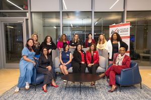 Group of professional women posing together indoors near a World Business Chicago banner for a networking event.