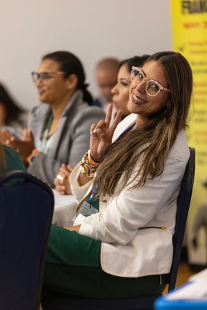 Student leaning back in classroom chairs while smiling and engaging in group discussion during class.