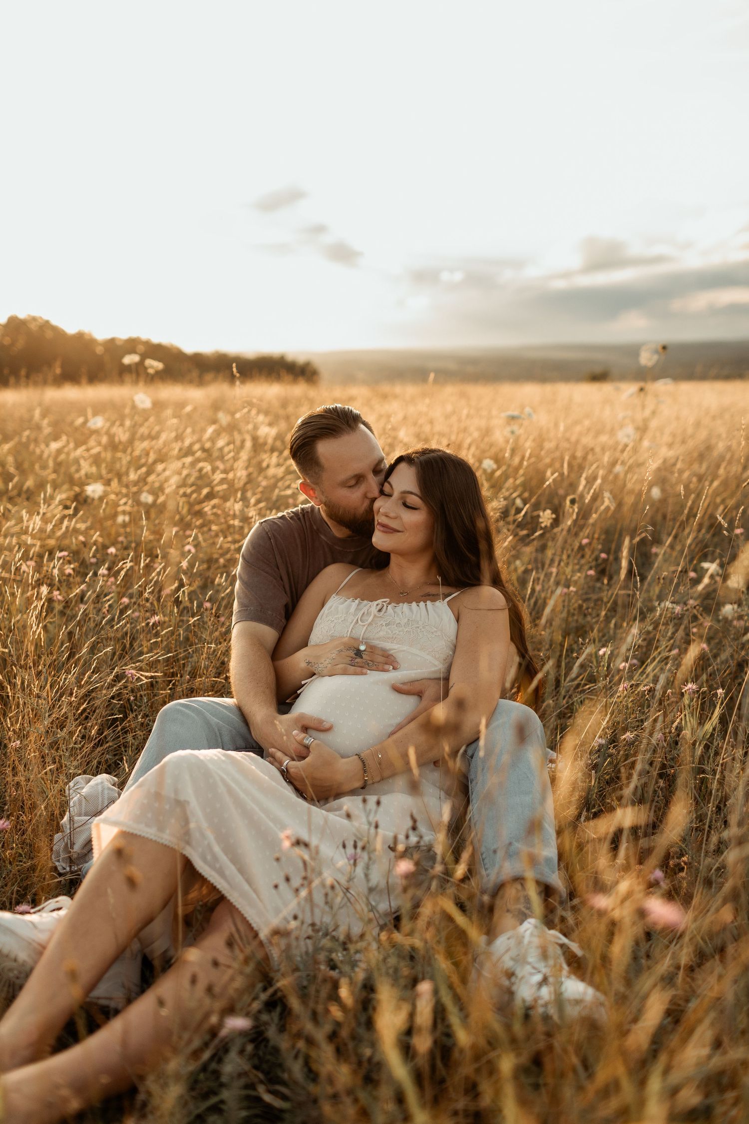 Family walks together through tall grass in golden sunlight during sunset in rural field.