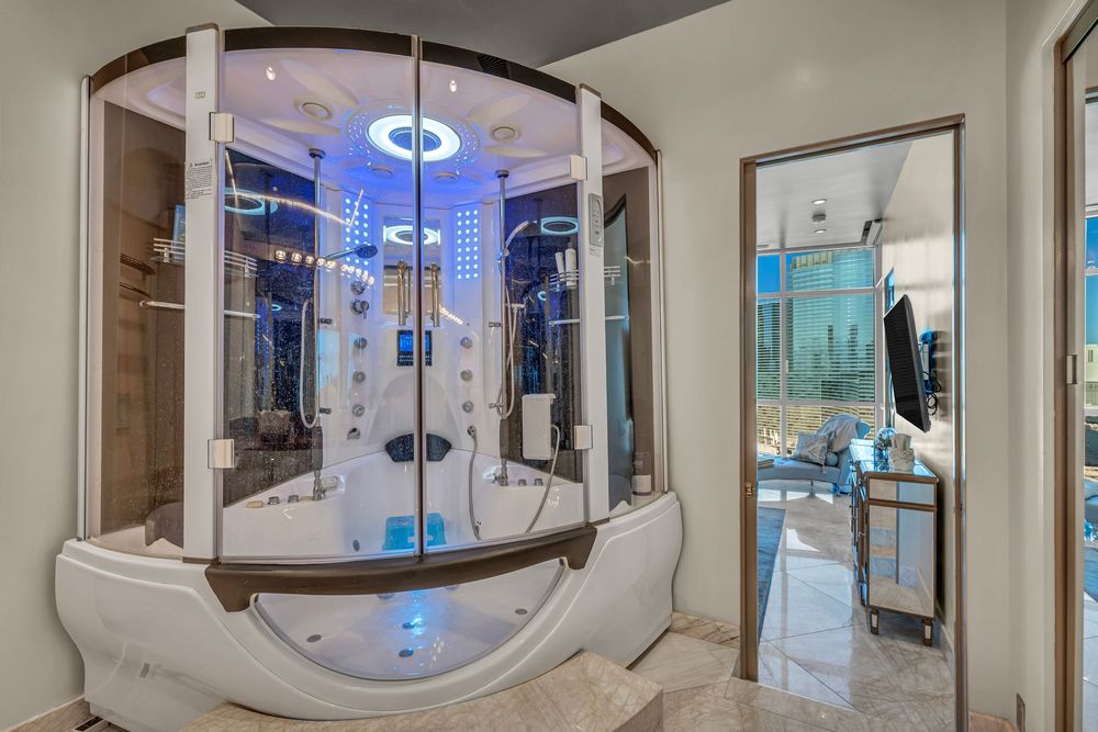 Luxurious steam shower enclosure with blue LED lighting and spa features in an upscale bathroom.