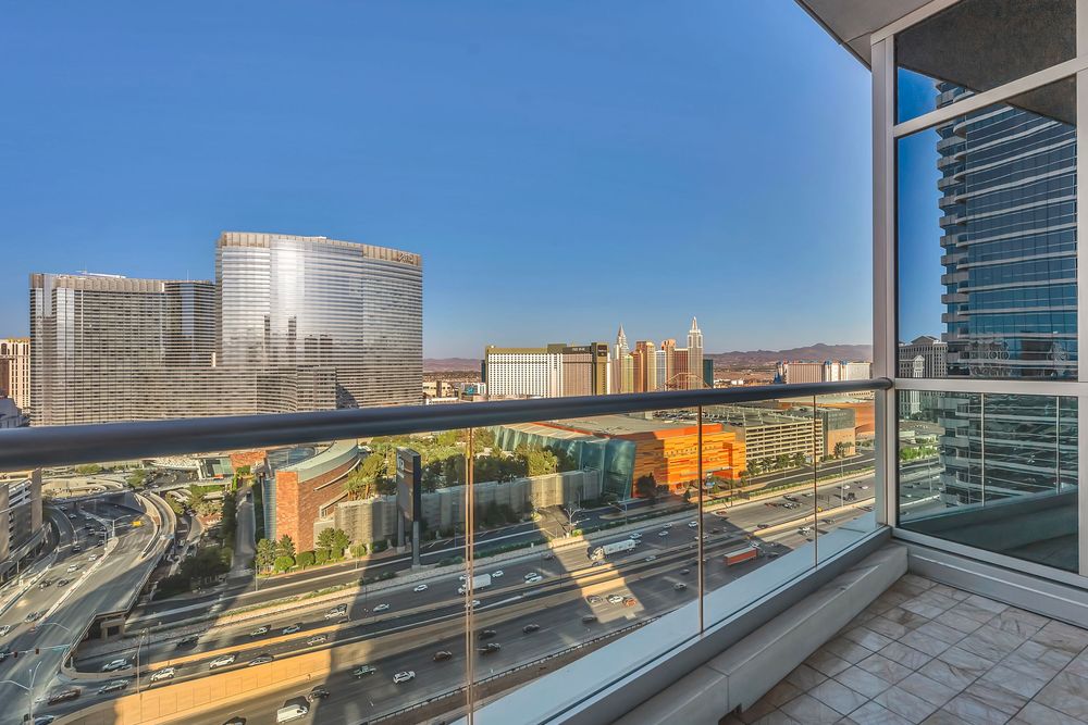 Stunning Las Vegas Strip cityscape view from a high-rise glass balcony on a clear sunny day.