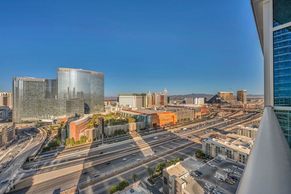 Panoramic aerial view of the Las Vegas Strip and surrounding cityscape from a luxury high-rise balcony.