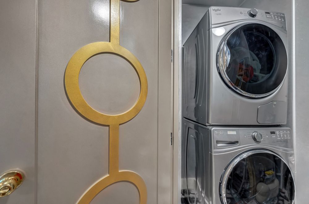 Stacked washer and dryer units behind a decorative gold circle-patterned laundry room door.
