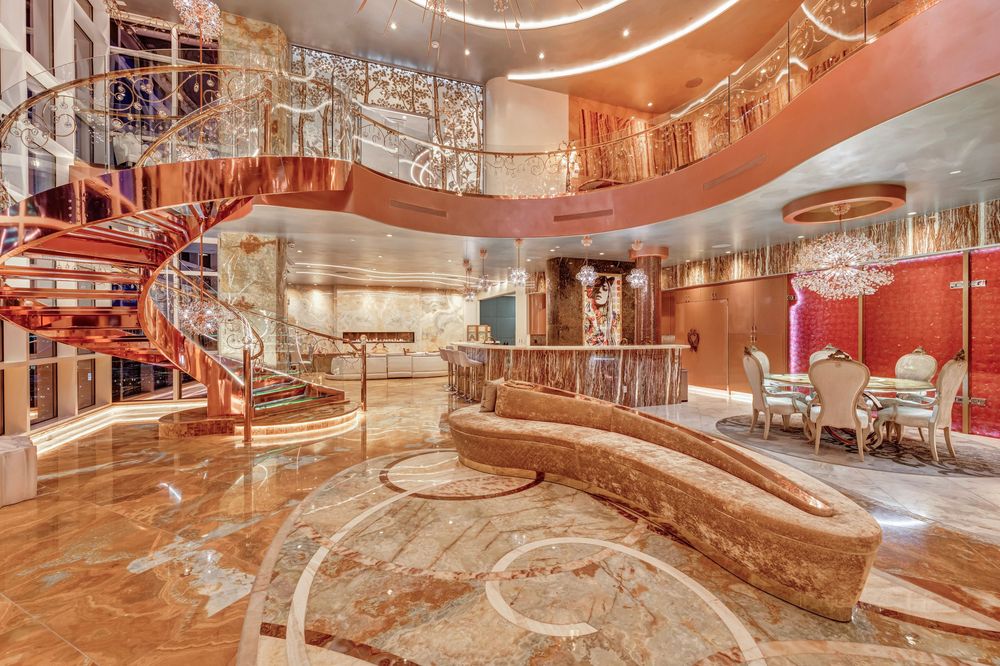Magnificent penthouse great room featuring a curved marble staircase, onyx bar, and crystal chandeliers.