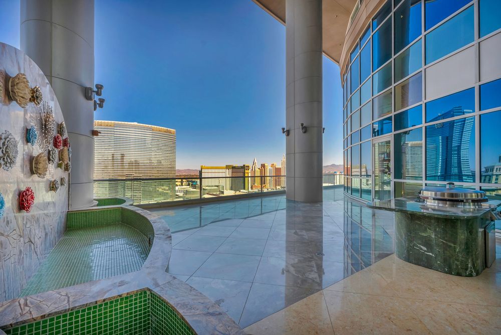 Expansive penthouse balcony with hot tub, glass railings, and stunning Las Vegas skyline views.