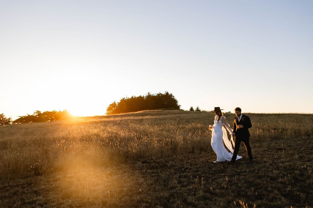 Silhouetted wedding party walking across a field during golden hour sunset. Mendocino wedding. Northern California.