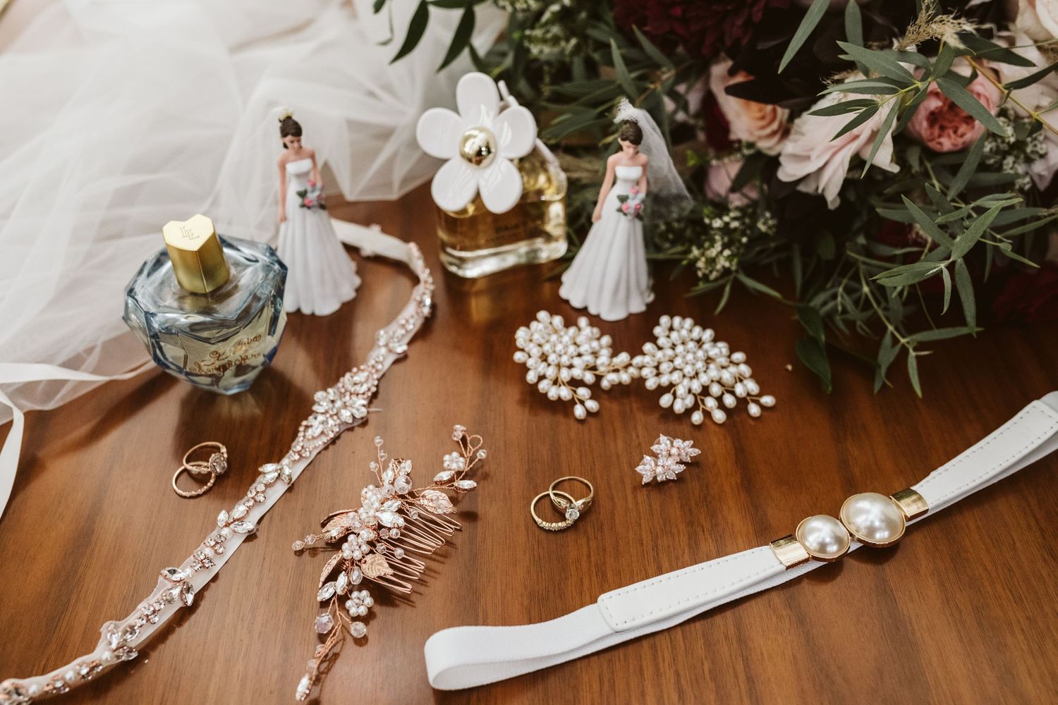 Wedding accessories including jewelry and ribbons arranged on a wooden surface.