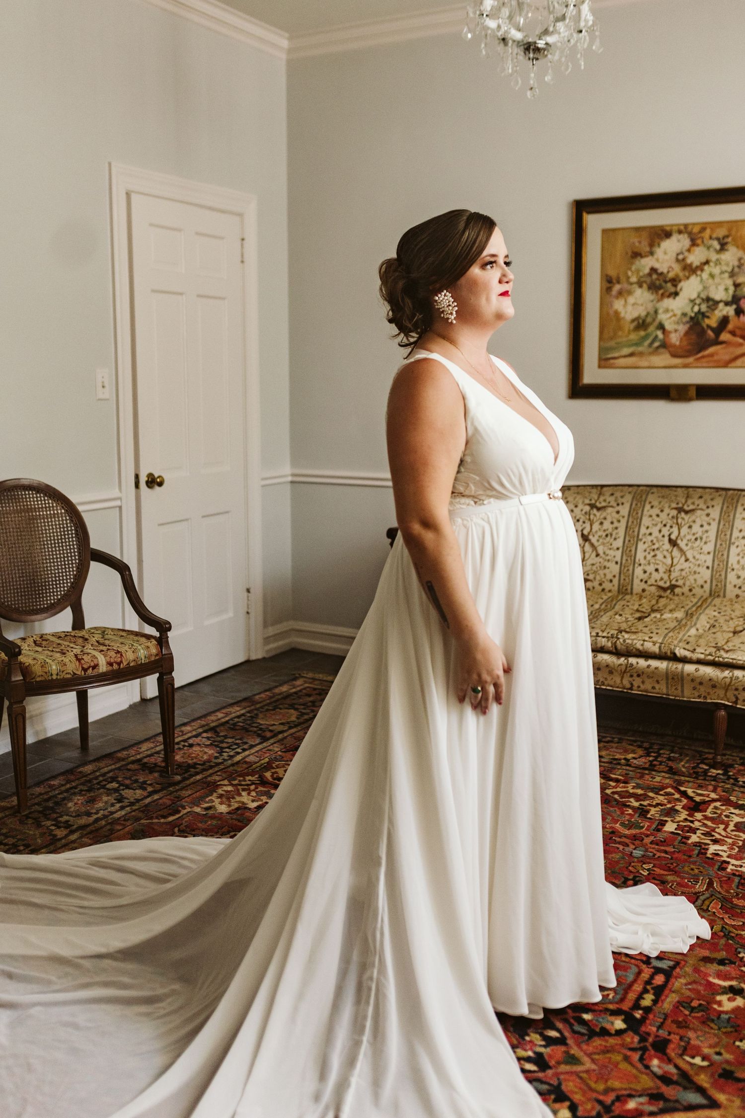 A wedding dress fitting in an elegant room with vintage furniture and a crystal chandelier.
