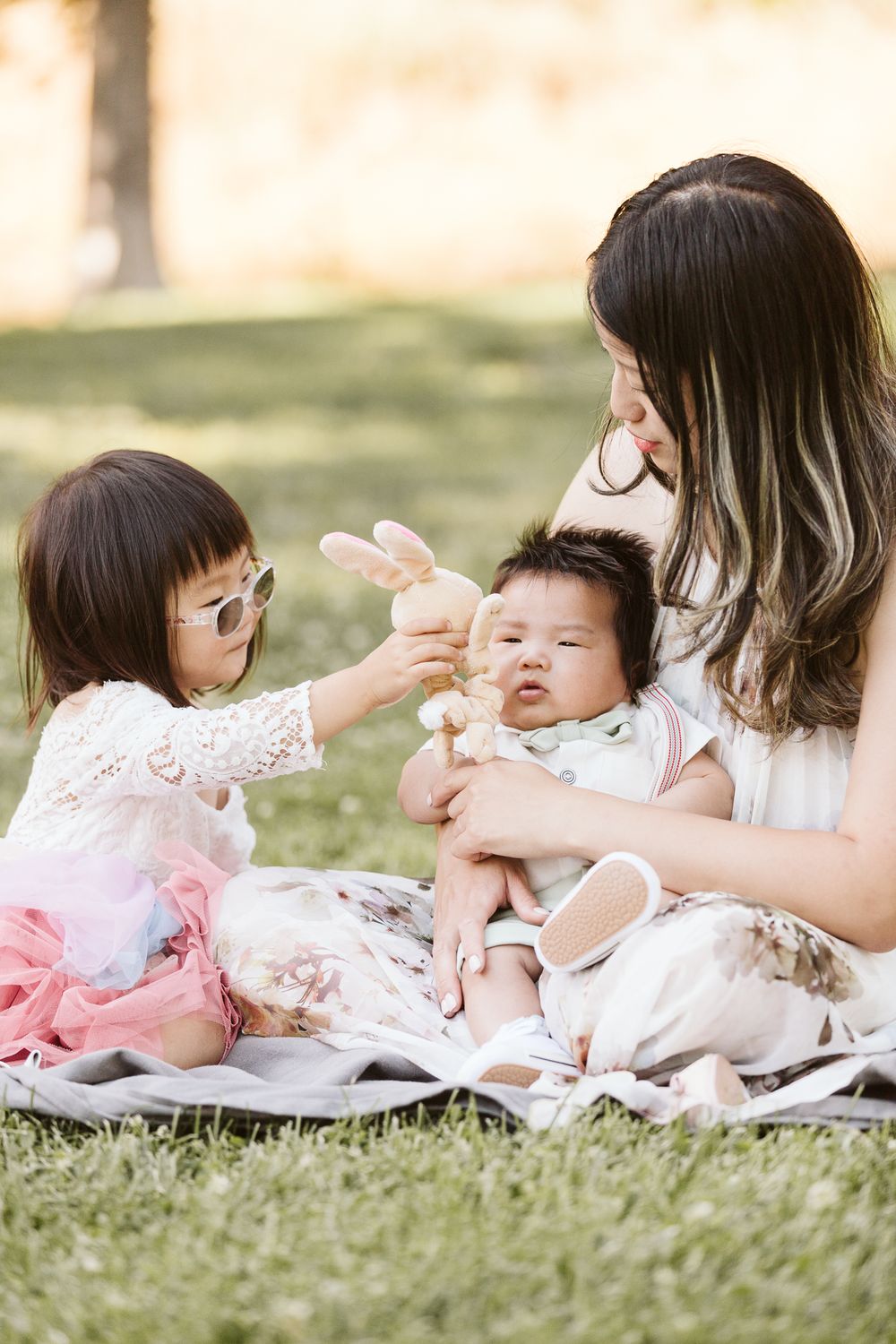 Family enjoying a picnic on grass as they interact with a baby.