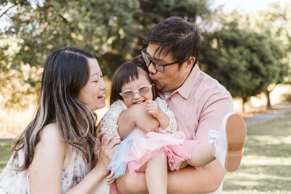 A family shares a joyful moment together outdoors in warm sunlight.