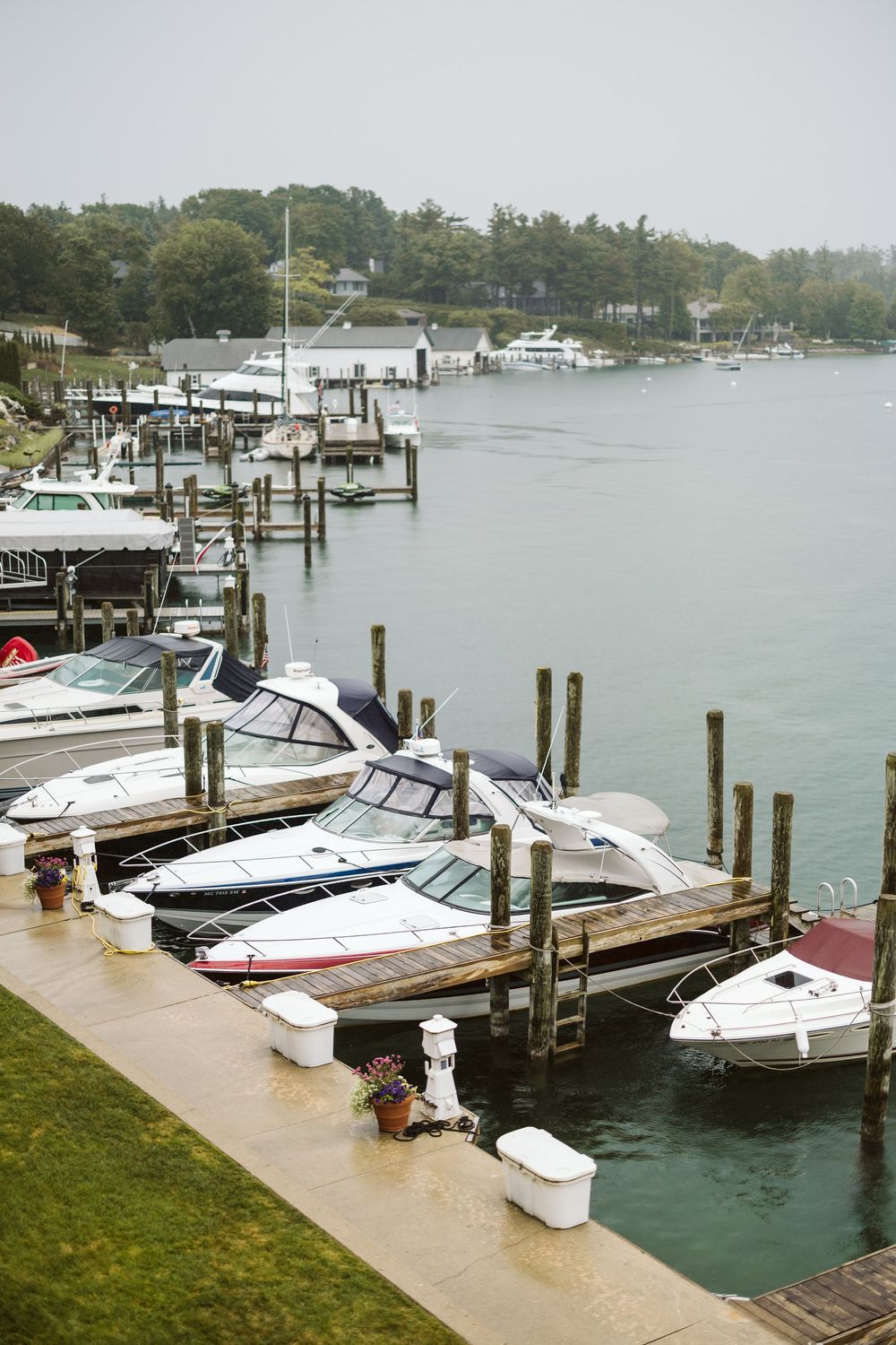 Boats docked at a marina on a foggy day, with wooden piers and calm water reflecting the overcast sky.