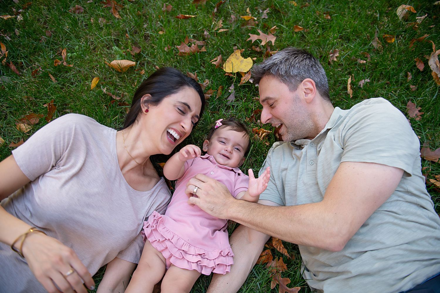 Family laying on grass sharing joyful moment together during autumn.
