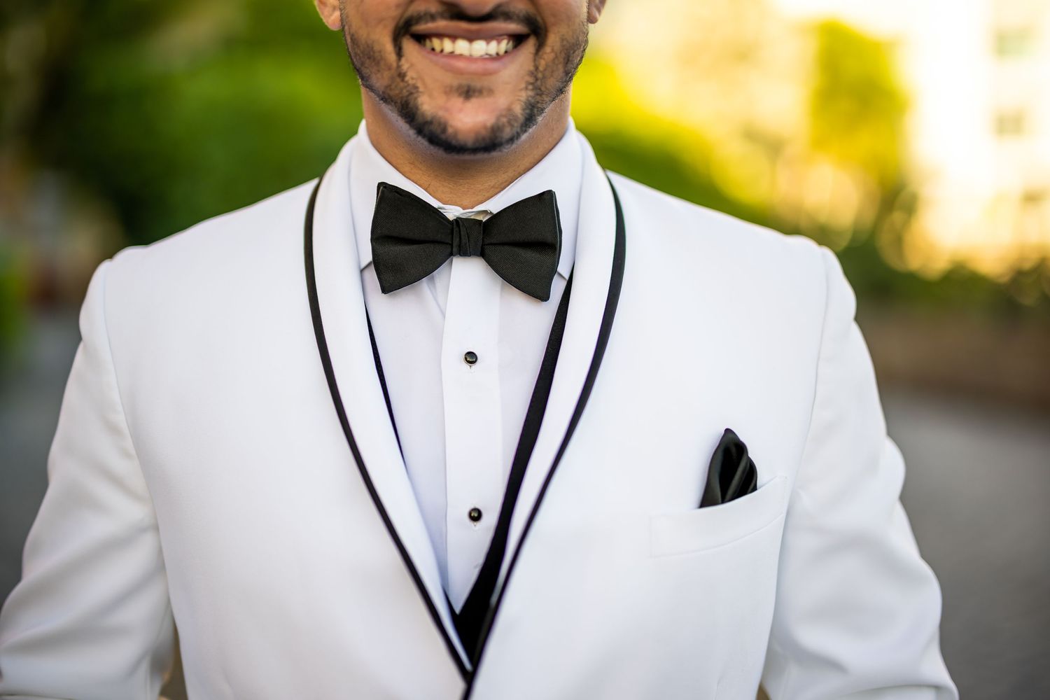 Close-up of white tuxedo jacket with black bow tie and pocket square.