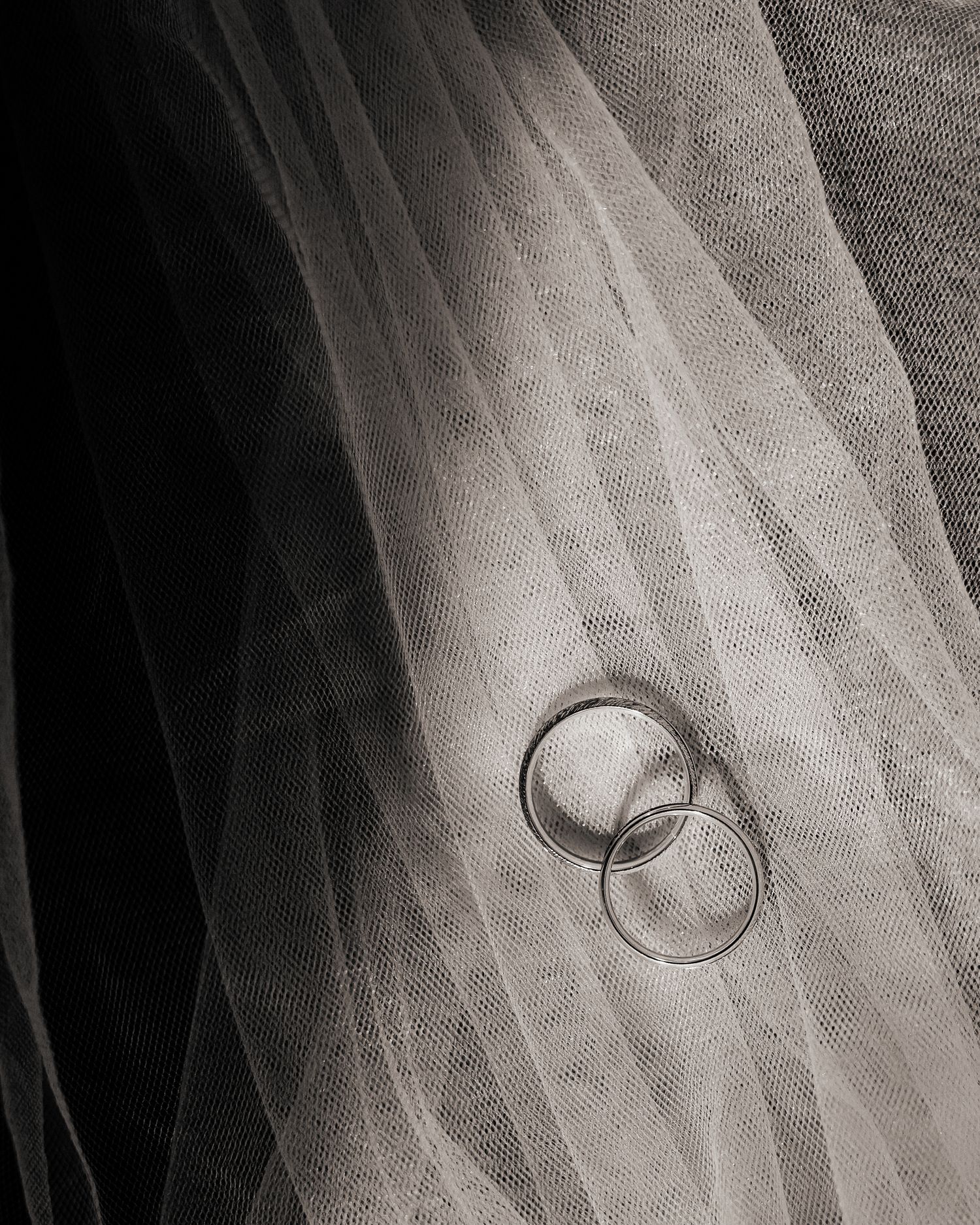 A bride and groom stand between grand neoclassical stone columns on marble steps during their wedding photo session.