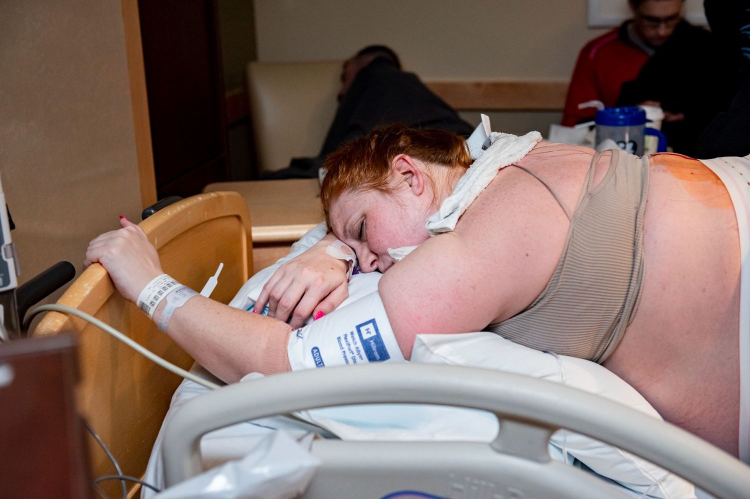 Laboring mom lies over the edge of the hospital bed