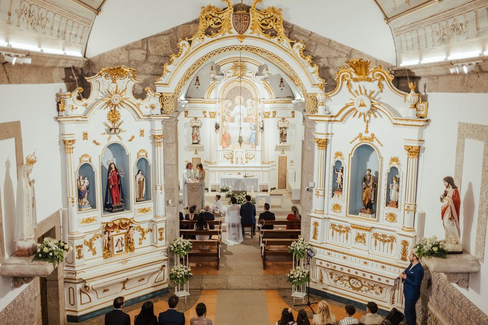 Ornate white and gold church altar during wedding ceremony with guests seated in pews.