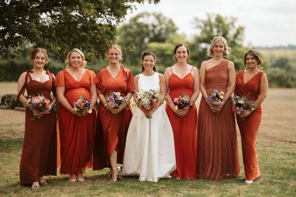 Bridesmaids in burnt orange terracotta dresses outside a Surrey wedding venue