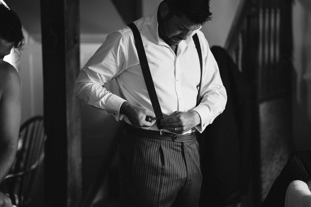 Groom getting dressed in black and white, wedding photography by Will Stedman Surrey