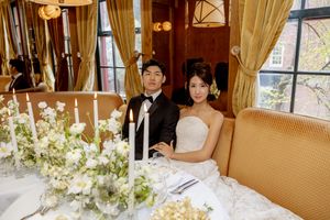 Asian bride and groom sit together at elegant sweetheart table with white floral arrangements at the Golden Swan Restaurant in New York City