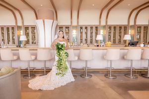 Bride in lace gown holding a cascading green bouquet poses at Wave Resort in Long Branch, NJ.